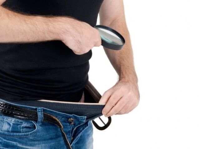 muž sa pozerá dolu nohavicami a chce si zväčšiť penis